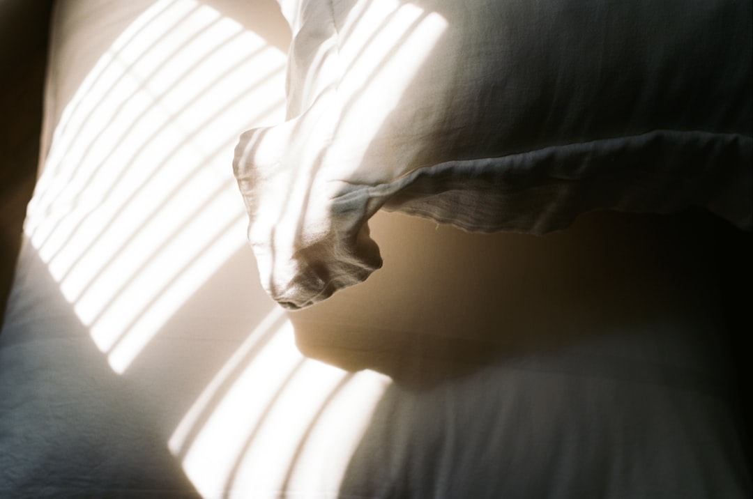 Person sitting calmly on the edge of a bed at night, glass of water on nightstand, soft lamplight, relaxed posture