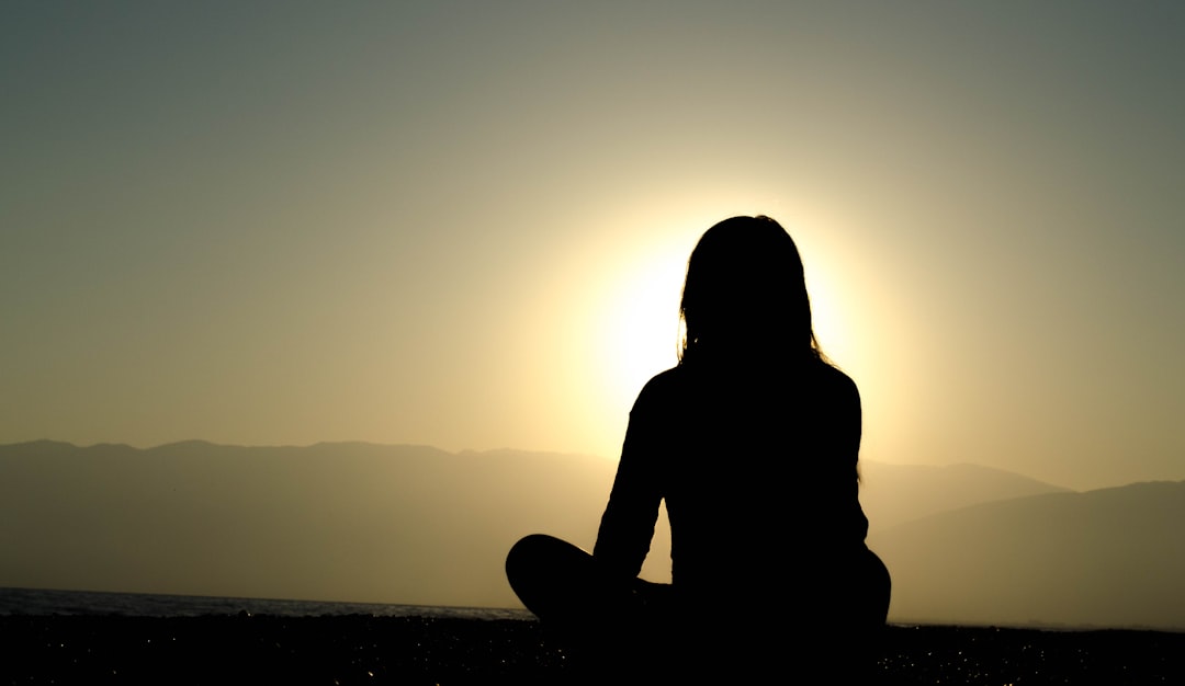 Person sitting by a sunlit window with a warm cup, eyes closed, looking genuinely at rest rather than just pausing