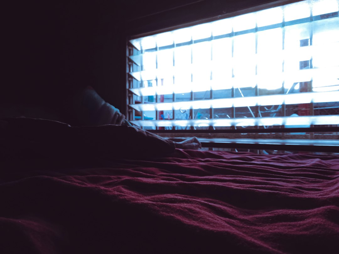 Soft bedside table with a glass of water, a single softgel capsule, and warm lamplight in the evening.