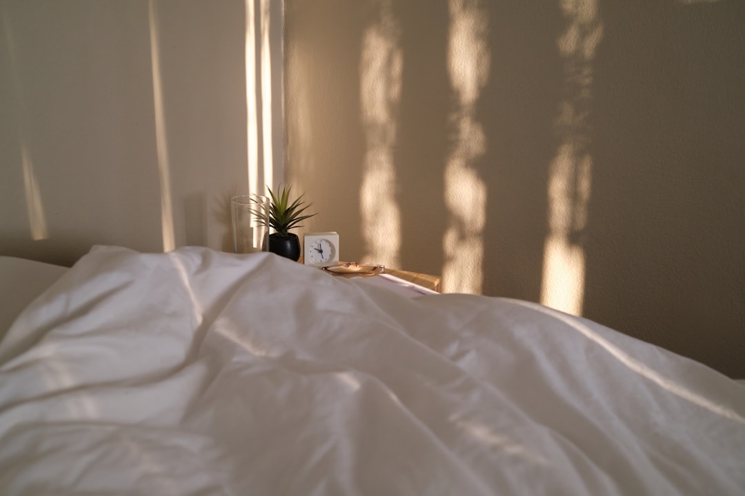 Softly lit bedroom at night with a book, glass of water, and a bottle of Good Night hemp softgels on a wooden nightstand