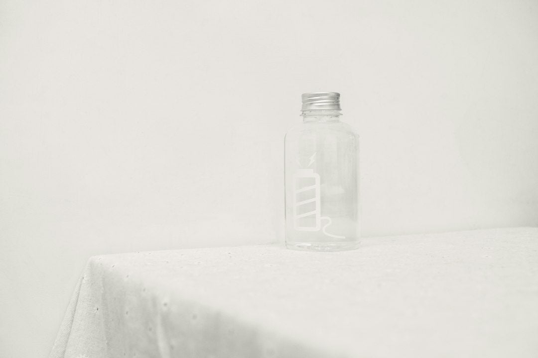 A single softgel capsule resting on a wooden surface beside a simple glass of water, morning light
