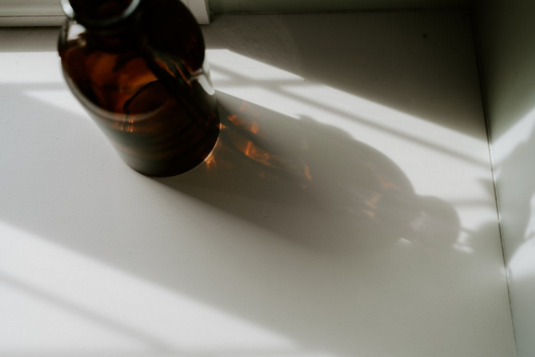 Softgel capsules arranged neatly beside a glass of water on a wooden morning table, calm and unhurried