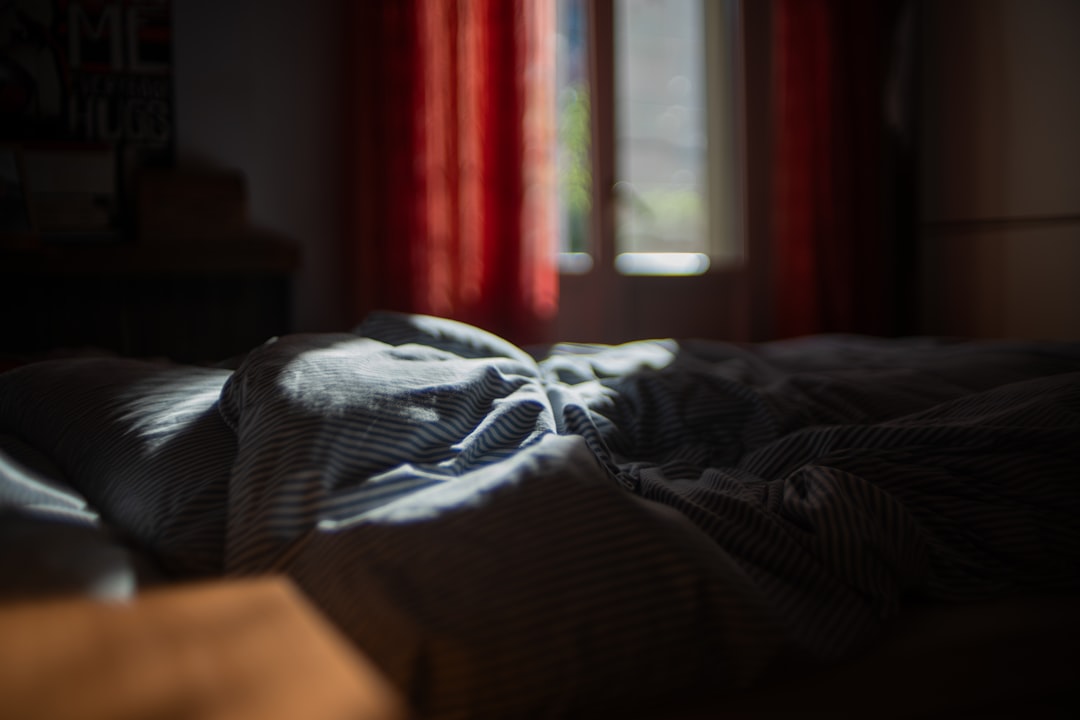 Person setting a softgel on a nightstand beside a dim lamp and an open book before bed